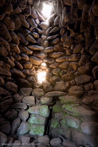 4) Nuraghe Aiga (40D_8140_1rid).jpg - Interno della sala al secondo piano. Sono visibili il foro sulla parte alta e la nicchia posta di fronte all'ingresso.La posizione del raggio di luce è quella delle ore 09:58 (le 10:58 dell'ora legale).